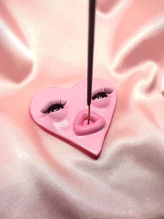 a pink heart shaped object with eyelashes sticking out of it