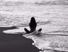 a woman sitting in the surf at the beach