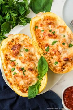 two spaghetti stuffed squash halves on a plate with sauce and parsley next to it