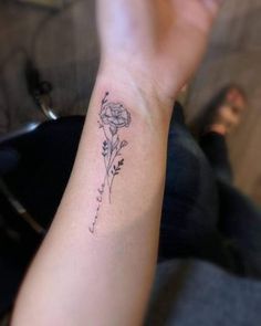 a woman's arm with a small flower tattoo on the left side of her wrist