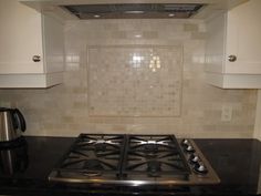 a stove top oven sitting inside of a kitchen next to white cabinets and counter tops