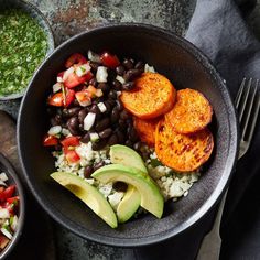 two bowls filled with different types of food next to a fork and knife on a table