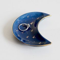 a blue and gold crescent shaped brooch with a diamond ring on it's side