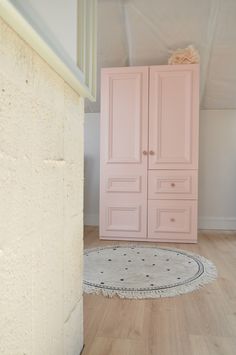 a room with a pink cabinet and rug on the floor