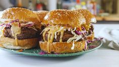 two hamburgers sitting on top of a green plate