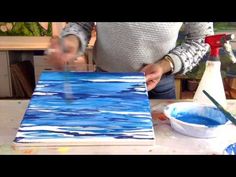 a person is painting on a canvas with blue paint