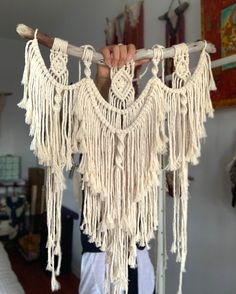 a person holding up a piece of white yarn with fringes hanging from it's sides