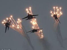 four fighter jets flying in formation with their lights on