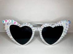 White Bride Sunglasses with white iridescent pearls and rainbow or gold letters White Sunglasses With Gradient Lenses As Gift, White Sunglasses With Gradient Lenses As A Gift, Personalized Sunglasses Wedding Favors, White Heart Sunglasses, Wedding Favors Sunglasses, Bridal Sunglasses, Sunglasses Wedding, Bride Sunglasses, Pearl Sunglasses