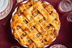 a pie sitting on top of a white plate next to glasses and plates with utensils