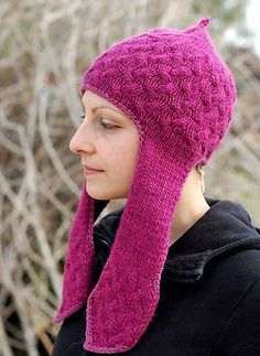 a woman wearing a pink knitted hat and scarf with her hair in the wind