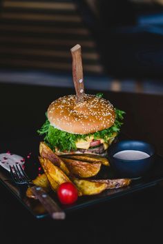 a hamburger and french fries on a black plate