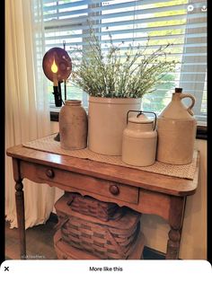 a wooden table topped with vases next to a window