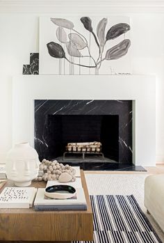 a living room with a fire place and art on the wall above it's mantle