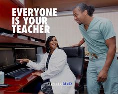 a woman sitting at a desk next to a man who is pointing at her computer