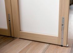 an open door on the floor in front of a white wall and wood flooring