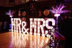 the letters mr and mrs are lit up in front of an empty stage with purple lights