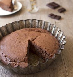 a chocolate pie sitting on top of a table next to a slice missing from it