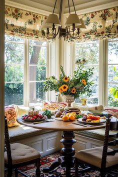 a dining room table with fruit and flowers in the window sill on top of it