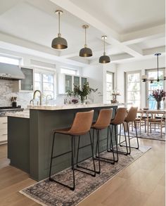 a kitchen with an island and bar stools in the center, surrounded by wooden flooring