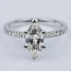 a pear shaped diamond ring with pave set diamonds on the band and side stones