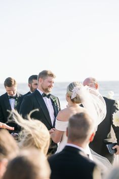 a bride and groom walking down the aisle at their wedding ceremony on the beach in front of an ocean