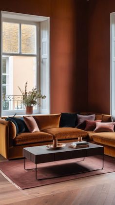 a living room filled with lots of furniture next to two large windows on top of a hard wood floor