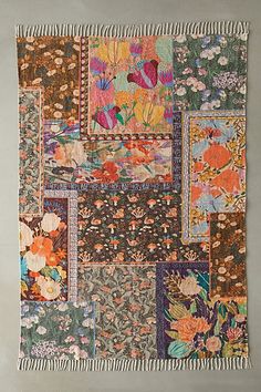 a multicolored patchwork wall hanging with flowers on it