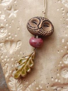 an owl ornament hanging from a string on a wall with leaves and acorns