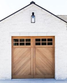 two wooden garage doors in front of a white brick building