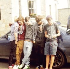 four young men standing in front of a car