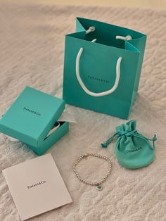 a bag, bracelet and ring sitting on top of a bed next to a box