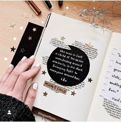 a woman's hand is holding an open book with writing on it and stars around her