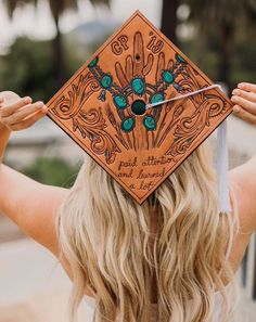 a woman with long blonde hair wearing a graduation cap that has an intricate design on it