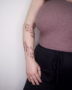 a woman with a tattoo on her left arm and wrist is standing in front of a white wall