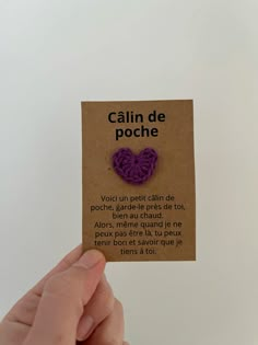 a person holding up a piece of paper with a purple heart on it that says calm de poche