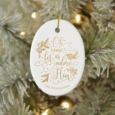 a christmas ornament hanging on a tree with gold foil lettering and pine cones