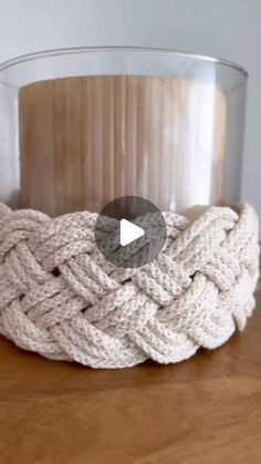 a glass vase with a rope wrapped around it on top of a wooden table next to a candle