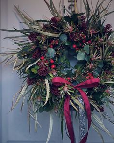 a wreath with red berries and greenery on the front door