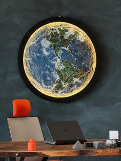 a desk with a laptop on it in front of a wall that has the earth painted on it