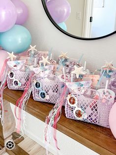 a table topped with lots of baskets filled with cake next to pink and blue balloons