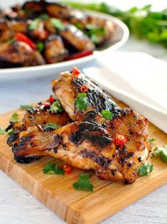 two pieces of chicken sitting on top of a wooden cutting board