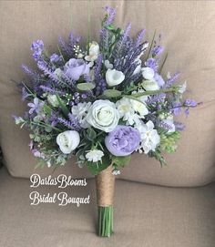 a bridal bouquet with lavenders, white and green flowers on a beige couch