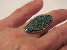 This ring is a lovely work of Native American art.  Probably Zuni.  The turquoise and coral are inlaid in the silver.  The ring is not marked sterling, but one can tell that it is sterling.  Native American artists did not always mark their silver items.  The length of the ring is 1 1/2 inches, and the width at the widest part in the center is 5/8 inch.   There is a lot of detail in the design of the ring, braided around the sides, and there is some design around the band of the ring as well. The size is about 6 1/2.  Shipping is free in the U.S. Traditional Silver Turquoise Ring With Inlay, Unique Silver Turquoise Ring With Inlay, Silver Turquoise Inlay Ring For Gift, Silver Turquoise Ring With Inlay For Gift, Vintage Native American Jewelry, Native American Rings, Native American Artists, New Hope, Coral Turquoise