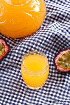 passion fruit is next to a glass of orange juice on a checkered tablecloth