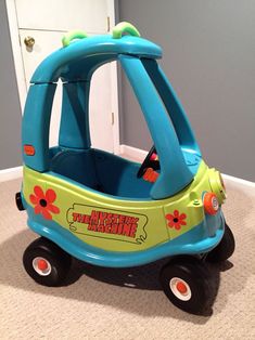 a blue and green toy car sitting on the floor next to a white door in a room