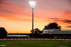 the sun is setting over a soccer field