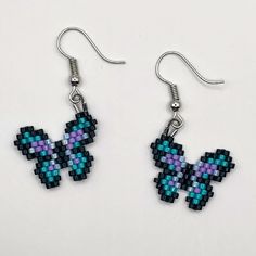 a pair of earrings with blue and purple beads on them sitting on a white surface