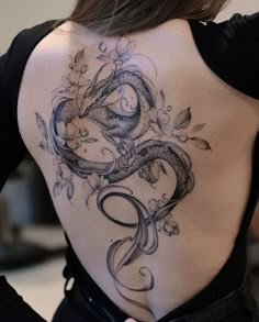 the back of a woman's body with an intricate tattoo design on her lower back