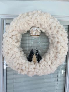 a white wreath with two black birds hanging on it's side and a window in the background